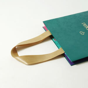 縦留め加工を施したサテンリボンハンドルが、上品な印象を与えるスキンケア・コスメブランドのクリスマスコフレ用オリジナル紙袋