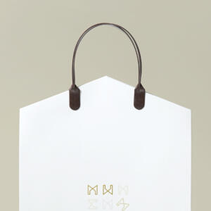 工務店をイメージした家の屋根型の口折りが特徴的な、ハンドルにハッピータックを使用したベリービーのオリジナル紙袋