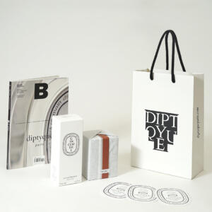 黒のアクリルスピンドルを使用した、モノトーンのデザインがエレガントなフレグランスブランドのオリジナル紙袋とパッケージ