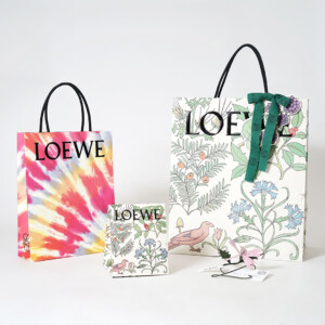 ロゴに浮き出し加工を施し、ワックスコードハンドルを使用した高級ファッションブランドの華やかなオリジナル紙袋