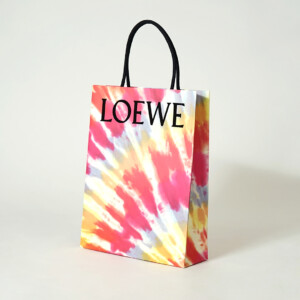 ロゴに浮き出し加工を施し、ワックスコードハンドルを使用した高級ファッションブランドの華やかなオリジナル紙袋