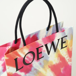 ロゴに浮き出し加工を施し、ワックスコードハンドルを使用した高級ファッションブランドの華やかなオリジナル紙袋