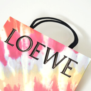 ロゴに浮き出し加工を施し、ワックスコードハンドルを使用した高級ファッションブランドの華やかなオリジナル紙袋