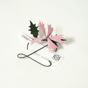 高級ファッションブランドの、ブランドシンボルを模した飾りが付いたアクセサリーとメッセージカード