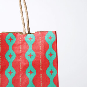 クラフト紙に華やかな模様が描かれた、有名コーヒーショップのホリデー仕様のオリジナル紙袋