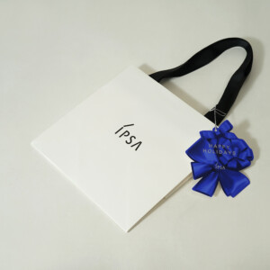 コスメブランドの鮮やかな青色チャームに、シルバーの箔押し加工が施された、ホリデー限定オリジナル紙袋