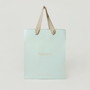 爽やかなブルーのボディに、くすみ感のあるベージュのアクリル平紐ハンドルを合わせた、フルーツ&デザートショップのオリジナル紙袋