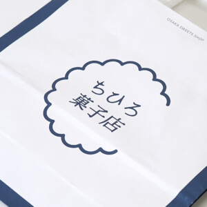 スイーツブランドの藍色の縁取りが上品な、世界観を伝える紙製ハンドルを採用したオリジナル紙袋