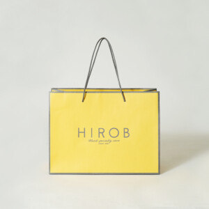 春らしいイエローのボディに、エンボス加工が施されたヴィンテージウォッチブランドのオリジナル紙袋