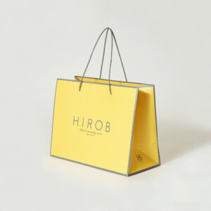 春らしいイエローのボディに、エンボス加工が施されたヴィンテージウォッチブランドのオリジナル紙袋