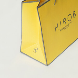 春らしいイエローのボディに、エンボス加工が施されたヴィンテージウォッチブランドのオリジナル紙袋