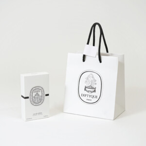 高級フレグランスメゾンの、浮き出し加工を施した大きなロゴが目を惹く、ホワイトベースのオリジナル紙袋とオリジナルボックス