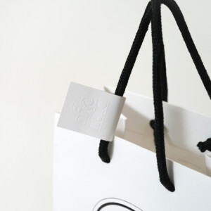 高級フレグランスメゾンの、浮き出し加工を施した大きなロゴが目を惹く、ホワイトベースのオリジナル紙袋