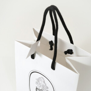 高級フレグランスメゾンの、浮き出し加工を施した大きなロゴが目を惹く、ホワイトベースのオリジナル紙袋