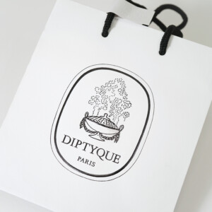 高級フレグランスメゾンの、浮き出し加工を施した大きなロゴが目を惹く、ホワイトベースのオリジナル紙袋