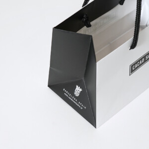 マチ部分にブランドURLを印刷した、スペイン王室御用達のチョコレートブランドによる、モノトーンでシックなオリジナル紙袋