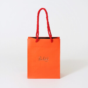 ショコラブランドの、ツイストロープがアクセントになった鮮やかなオレンジカラーのオリジナル紙袋