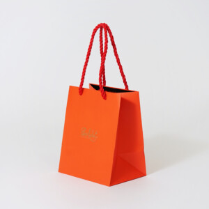 ショコラブランドの、ツイストロープがアクセントになった鮮やかなオレンジカラーのオリジナル紙袋