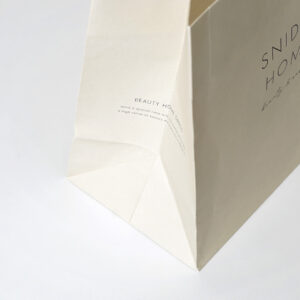 美容効果を追求したルームウェアブランドが手がける、マチ部分にブランドコンセプトをプリントした、アイボリー色の清潔感あるオリジナル紙袋