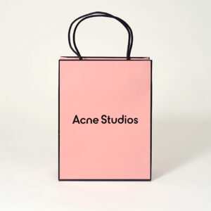 コーラルピンクを全面印刷で表現し、ロゴに箔押し加工が施した、有名ファッションブランドのリニューアルしたオリジナル紙袋