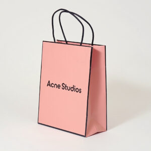 コーラルピンクを全面印刷で表現し、ロゴに箔押し加工が施した、有名ファッションブランドのリニューアルしたオリジナル紙袋