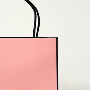 コーラルピンクを全面印刷で表現し、ロゴに箔押し加工が施した、有名ファッションブランドのリニューアルしたオリジナル紙袋