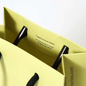 韓国コスメブランドが手がける、口折り部分に店舗情報がプリントされた、トレンド感溢れるイエローベースのオリジナル紙袋