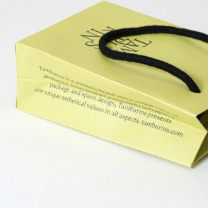 韓国コスメブランドが手がける、側面にブランドコンセプトがプリントされた、トレンド感溢れるイエローベースのオリジナル紙袋