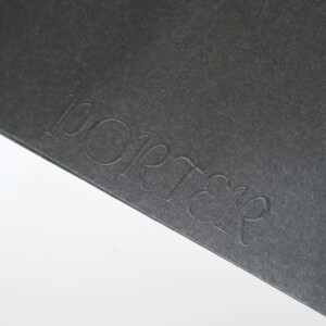 歴史ある鞄メーカーのブランド名にエンボス加工が施された、インパクトのあるオリジナル紙袋 