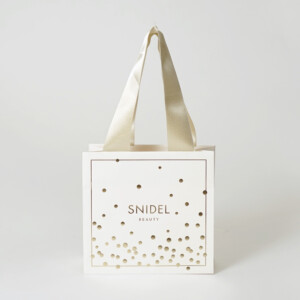 マットPP加工を施したボディに箔押し加工でドット模様とロゴを印字した、コスメブランドの高級感あふれるオリジナル紙袋