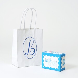 スイーツ専門店の縦留めハンドルのオリジナル紙袋と、ゴールドの箔押し加工が施されたオリジナルボックス