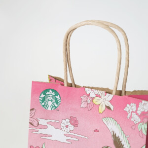 フレキソ印刷を用いて春らしい景色を描いた、コーヒーショップの桜色のオリジナル紙袋