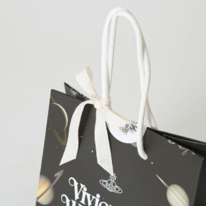 ブランドロゴがプリントされたリボンがハンドルに巻きつけ、ギフト感を強めた、イギリス発アパレルブランドの神秘的でロックなオリジナル紙袋