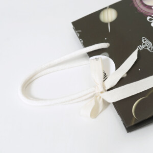 ハンドルにホワイトのアクリルスピンドルを使用した、イギリス発アパレルブランドの神秘的でロックなオリジナル紙袋