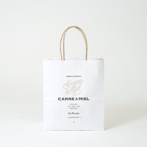 クラフトのような優しい風合いの用紙に、紙丸紐のハンドルを使用した、キャラメル×チョコレート専門ブランドのオリジナル紙袋