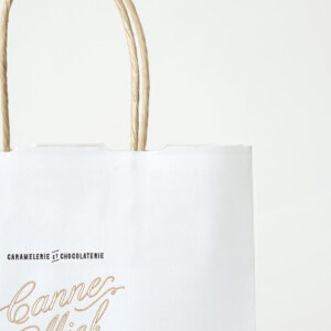 クラフトのような優しい風合いの用紙に、紙丸紐のハンドルを使用した、キャラメル×チョコレート専門ブランドのオリジナル紙袋