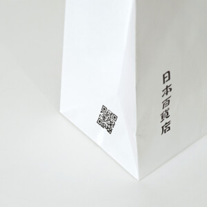 シンプルな縦留めのハンドルを採用した、食と雑貨のセレクトショップのオリジナル紙袋