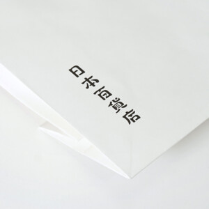 シンプルな縦留めのハンドルを採用した、食と雑貨のセレクトショップのオリジナル紙袋