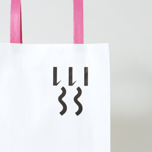 シンプルな縦留めのハンドルを採用した、食と雑貨のセレクトショップのオリジナル紙袋