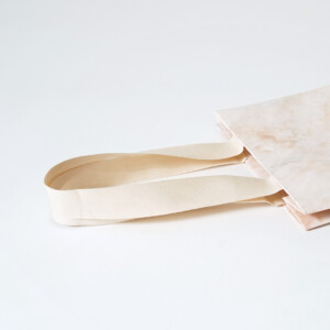 コットン素材のハンドルが縦留め加工された、ジュエリーブランドのエレガントなオリジナル紙袋