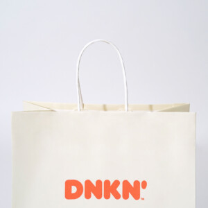 晒クラフト紙にポップなカラーリングとデザインが施された、有名ドーナツ&コーヒー専門店のオリジナル紙袋