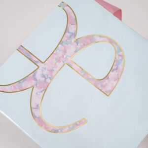 ゴールドの箔押し加工で装飾されたロゴマークが美しい、高級コスメブランドのオリジナル紙袋