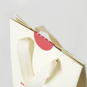 ロゴが印象的な、世界的人気ファッションブランドの口留めシールと箔押し加工が施された、スタイリッシュなオリジナル紙袋