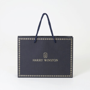 ネイビーの紙袋に上品なゴールドの箔押しロゴが目を惹く、高級ジュエリーブランドのエレガントなオリジナル紙袋