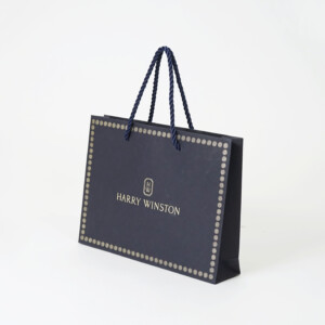 ネイビーの紙袋に上品なゴールドの箔押しロゴが目を惹く、高級ジュエリーブランドのエレガントなオリジナル紙袋