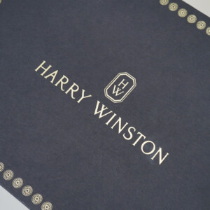 ネイビーの紙袋に上品なゴールドの箔押しロゴが目を惹く、高級ジュエリーブランドのエレガントなオリジナル紙袋