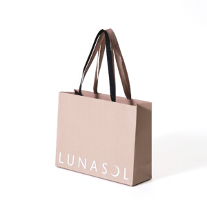 くすみ感のあるベージュカラーのボディにエンボス加工と箔押しが施された、高級コスメブランドのエレガントなオリジナル紙袋