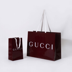 深い赤色のボディに、グロス加工とホワイトの箔押し加工が施された、ラグジュアリーブランドの高級感あふれるオリジナル紙袋