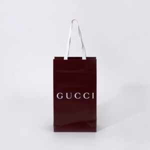 深い赤色のボディに、グロス加工とホワイトの箔押し加工が施された、ラグジュアリーブランドの高級感あふれるオリジナル紙袋
