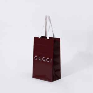 深い赤色のボディに、グロス加工とホワイトの箔押し加工が施された、ラグジュアリーブランドの高級感あふれるオリジナル紙袋